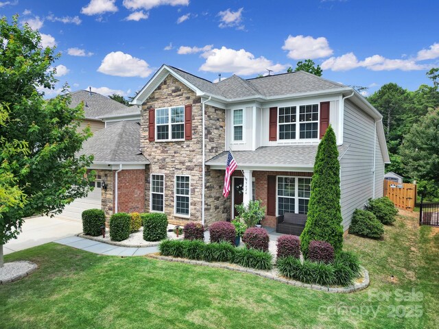 5424 Tilley Manor Dr, Matthews, NC 28105 - traditional-style house with a shingled roof, concrete driveway, stone siding, an attached garage, and covered porch