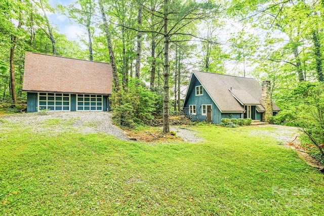 193 Falls View Dr, Lake Toxaway, NC 28747 - view of front facade with a chimney, a front yard, a garage, roof with shingles, and an outbuilding