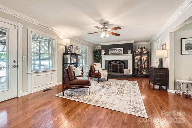 1175 18th Ave NE, Hickory, NC 28601 - living room with hardwood / wood-style flooring, healthy amount of natural light, a ceiling fan, a fireplace with raised hearth, and crown molding