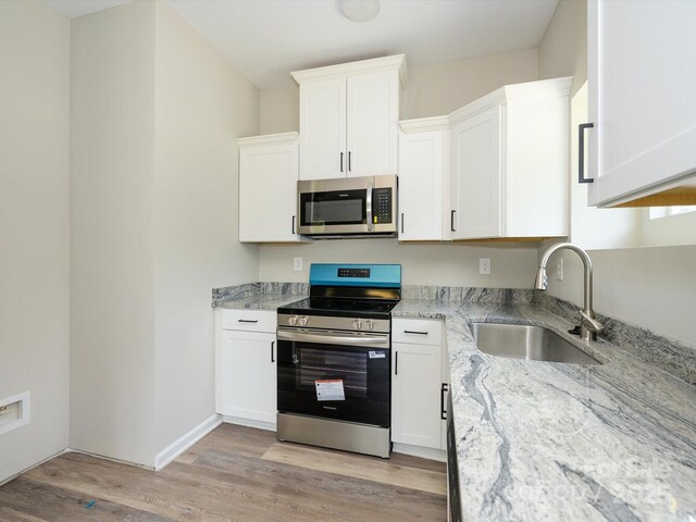 102 Mobley St, Clover, SC 29710 - kitchen featuring appliances with stainless steel finishes, light stone countertops, light wood-style floors, and white cabinets