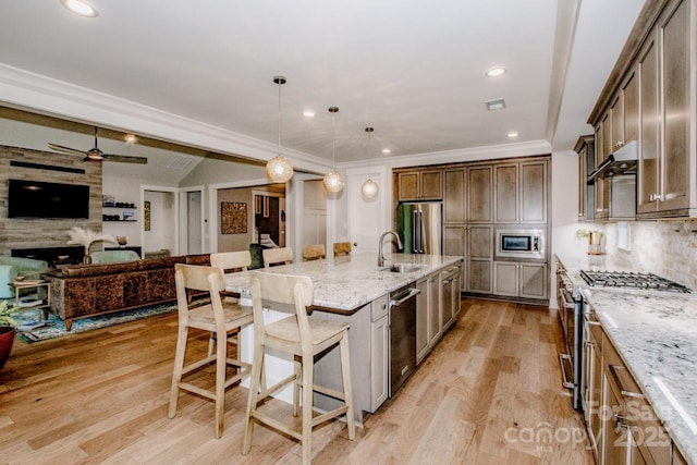 13708 Huntson Park Ln, Huntersville, NC 28078 - kitchen featuring appliances with stainless steel finishes, light stone counters, light wood-style flooring, open floor plan, and a kitchen breakfast bar