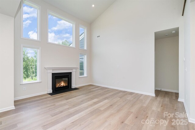 18019 Wilbanks Dr, Charlotte, NC 28278 - unfurnished living room with high vaulted ceiling, light wood-style floors, a fireplace with flush hearth, and baseboards