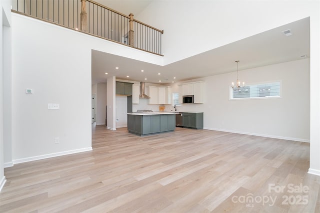 18019 Wilbanks Dr, Charlotte, NC 28278 - unfurnished living room featuring a chandelier, light wood-style floors, a sink, baseboards, and a high ceiling