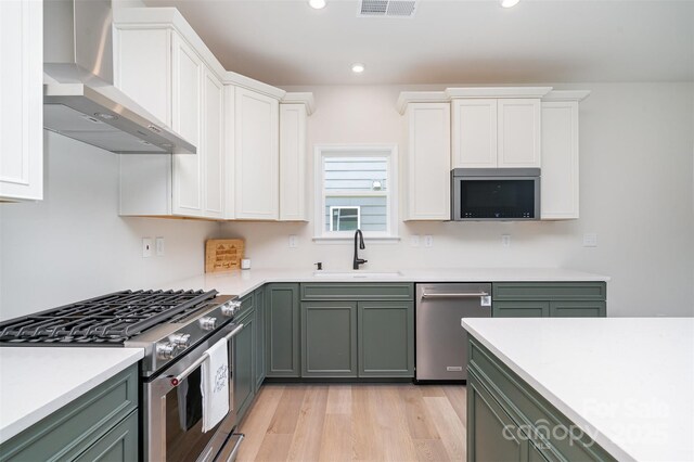 18019 Wilbanks Dr, Charlotte, NC 28278 - kitchen with wall chimney exhaust hood, stainless steel appliances, a sink, green cabinetry, and light countertops