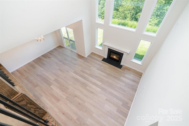 18019 Wilbanks Dr, Charlotte, NC 28278 - unfurnished living room with a fireplace with flush hearth, light wood-style floors, a high ceiling, a chandelier, and baseboards