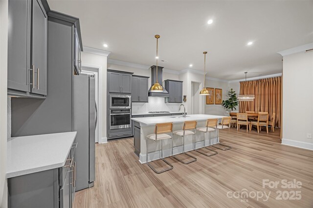 513 Meadow Ridge Dr, Belmont, NC 28012 - kitchen featuring wall chimney range hood, appliances with stainless steel finishes, gray cabinetry, a sink, and a breakfast bar