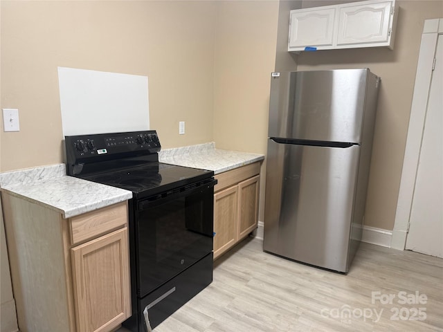 2017 Ashley Rd, Charlotte, NC 28208 - kitchen with freestanding refrigerator, black electric range oven, light wood-type flooring, and light countertops
