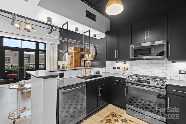 720 Governor Morrison St Unit 219, Charlotte, NC 28211 - kitchen featuring appliances with stainless steel finishes, dark cabinetry, a peninsula, and tasteful backsplash