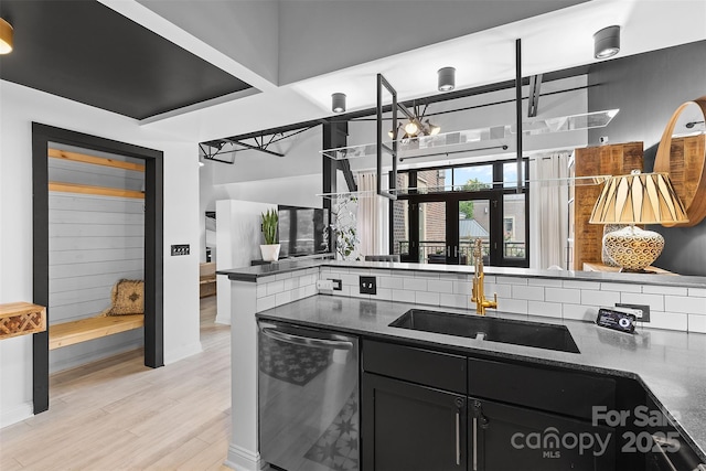 720 Governor Morrison St Unit 219, Charlotte, NC 28211 - kitchen featuring dishwasher, dark cabinetry, dark countertops, light wood-style floors, and backsplash
