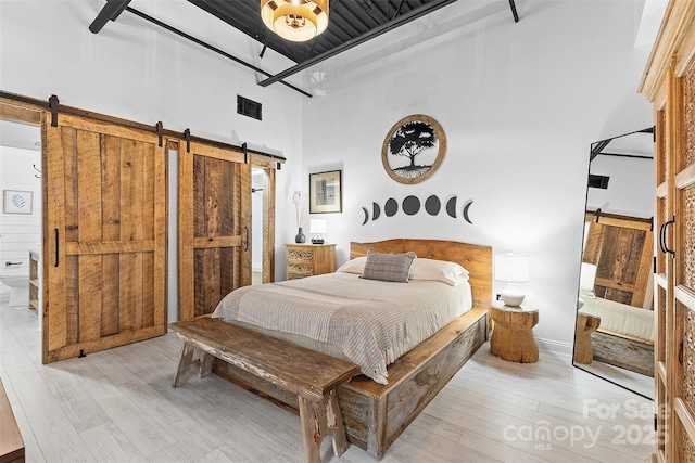 720 Governor Morrison St Unit 219, Charlotte, NC 28211 - bedroom with a barn door, a towering ceiling, and light wood finished floors