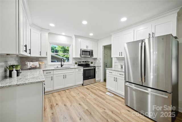 6127 Eagle Peak Dr, Charlotte, NC 28214 - kitchen with appliances with stainless steel finishes, light wood-type flooring, white cabinets, backsplash, and light stone countertops
