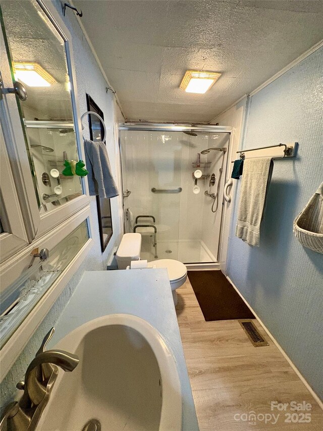 5022 Wrenn Dr, Denver, NC 28037 - full bathroom featuring wood finished floors, toilet, a sink, a stall shower, and a textured ceiling