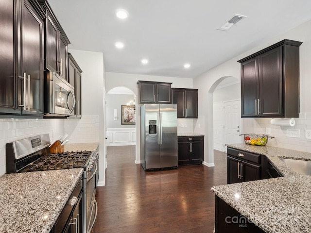 417 Livingston Dr, Lancaster, SC 29720 - kitchen with stainless steel appliances, arched walkways, light stone counters, dark wood finished floors, and backsplash