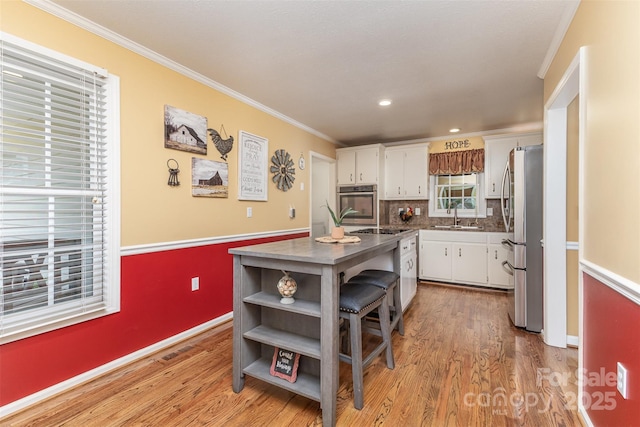 3060 Texs Fish Camp Rd, Connelly Springs, NC 28612 - kitchen with appliances with stainless steel finishes, white cabinets, light wood-style flooring, a center island, and crown molding