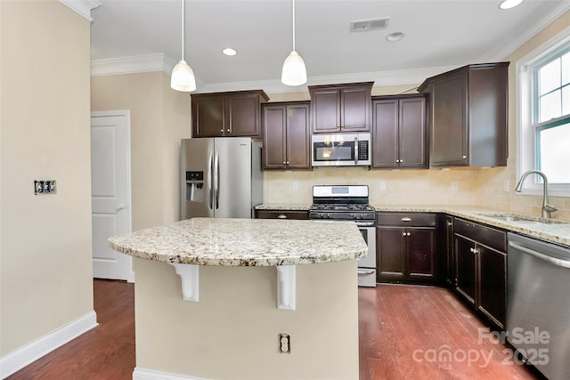 10004 Perth Moor Rd, Charlotte, NC 28278 - kitchen featuring appliances with stainless steel finishes, a sink, a kitchen island, dark wood finished floors, and ornamental molding