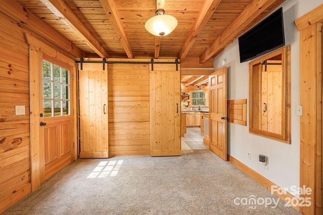 447 Hidden Lake Pkwy, Nebo, NC 28761 - unfurnished bedroom featuring a barn door, wooden ceiling with exposed beams, light carpet, wood walls, and baseboards