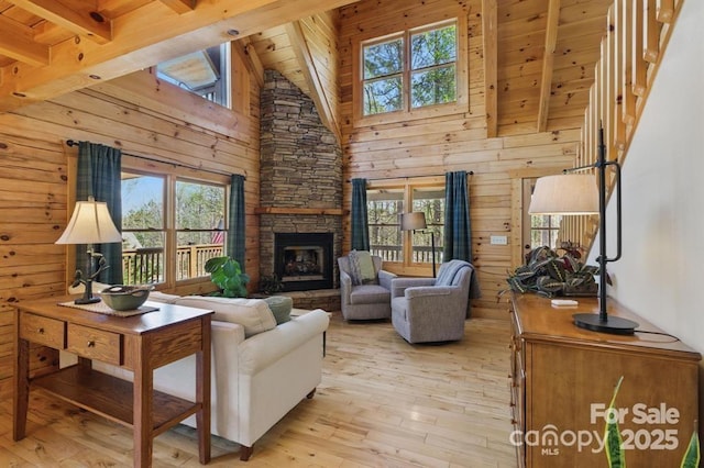 447 Hidden Lake Pkwy, Nebo, NC 28761 - living room featuring light wood-style floors, healthy amount of natural light, wooden ceiling with exposed beams, a stone fireplace, and wooden walls