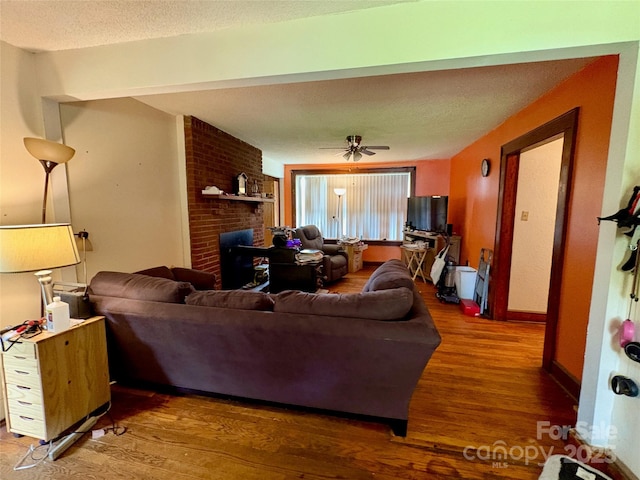 78 Moffitt Hill Church Rd, Old Fort, NC 28762 - living area featuring wood finished floors, a brick fireplace, a ceiling fan, a textured ceiling, and baseboards