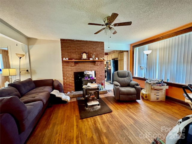 78 Moffitt Hill Church Rd, Old Fort, NC 28762 - living area with a textured ceiling, wood-type flooring, ceiling fan, a brick fireplace, and plenty of natural light