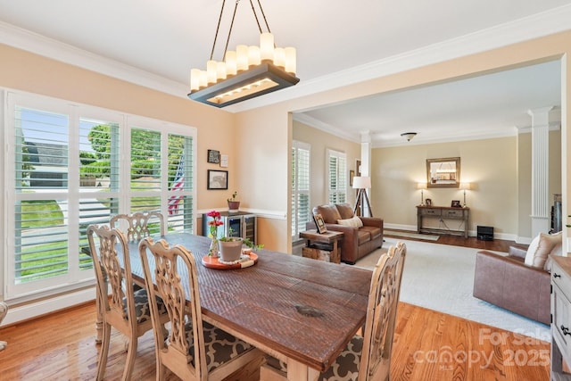 207 Spaniel Dr SE, Concord, NC 28025 - dining area with plenty of natural light, light wood-style flooring, crown molding, decorative columns, and a chandelier
