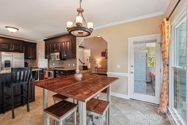 207 Spaniel Dr SE, Concord, NC 28025 - dining room with arched walkways, crown molding, light tile patterned flooring, and a chandelier