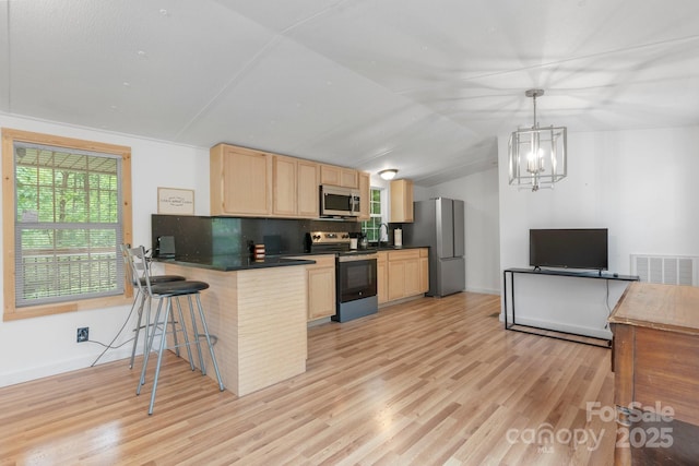 8692 Lambs Way, Connelly Springs, NC 28612 - kitchen featuring appliances with stainless steel finishes, light brown cabinetry, dark countertops, lofted ceiling, and a peninsula