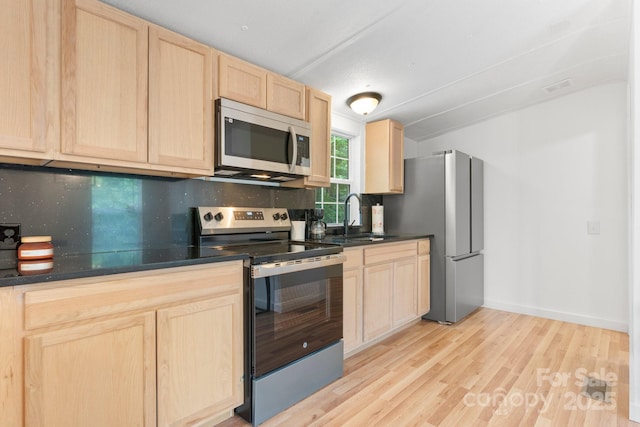 8692 Lambs Way, Connelly Springs, NC 28612 - kitchen featuring appliances with stainless steel finishes, light brown cabinets, a sink, dark countertops, and light wood-style flooring