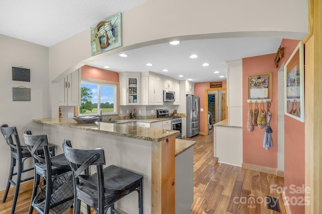 333 Lambs Grill Rd, Rutherfordton, NC 28139 - kitchen with stainless steel appliances, a peninsula, a breakfast bar area, arched walkways, and light wood-style flooring