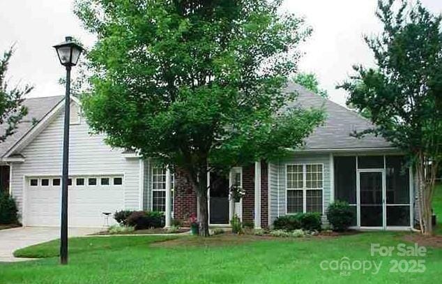 4492 Antelope Ln, Charlotte, NC 28269 - obstructed view of property featuring concrete driveway, an attached garage, a front lawn, and a sunroom