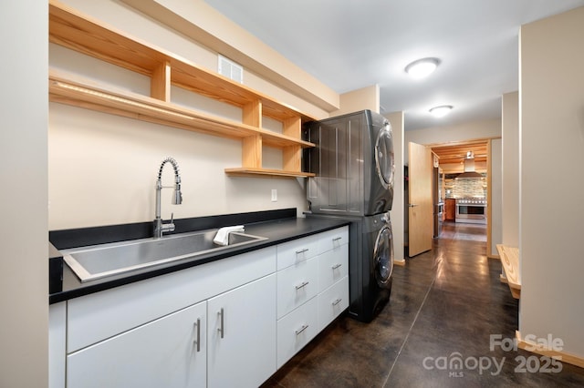 588 Long Branch Rd, Swannanoa, NC 28778 - kitchen with stacked washing machine and dryer, a sink, dark countertops, finished concrete flooring, and wall chimney range hood