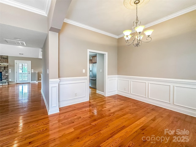 1625 Damascus Cir, Conover, NC 28613 - spare room featuring a chandelier, crown molding, light wood-style floors, wainscoting, and a fireplace