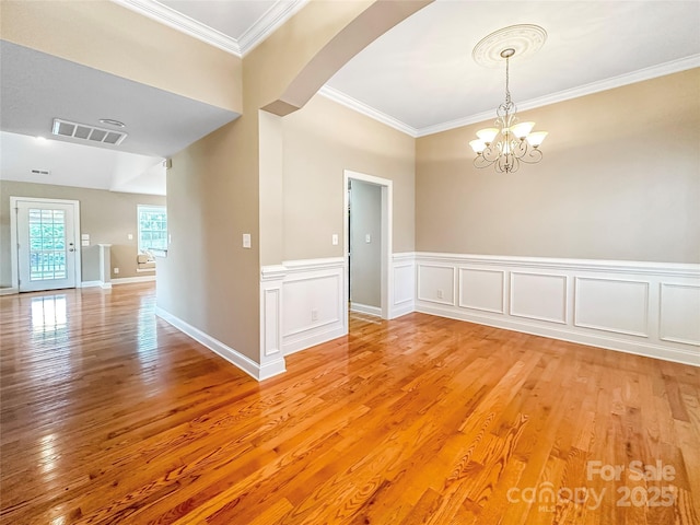 1625 Damascus Cir, Conover, NC 28613 - empty room featuring light wood-style flooring, arched walkways, crown molding, a chandelier, and wainscoting