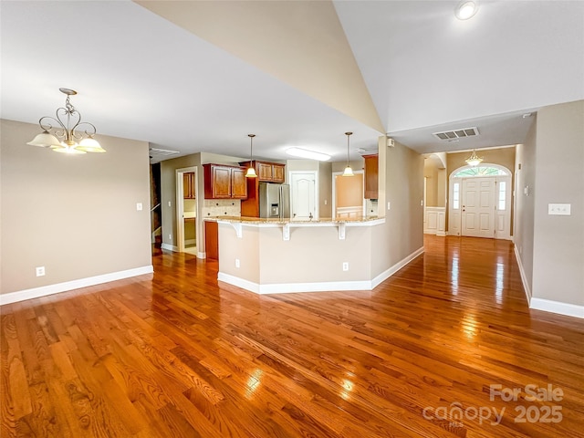 1625 Damascus Cir, Conover, NC 28613 - kitchen with stainless steel fridge, wood finished floors, a kitchen breakfast bar, a peninsula, and brown cabinets