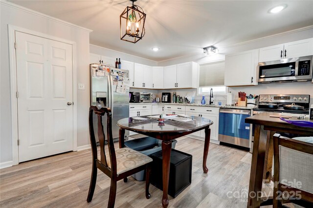 812 Kings Rd, Shelby, NC 28150 - kitchen featuring stainless steel appliances, ornamental molding, light wood-style floors, white cabinetry, and pendant lighting