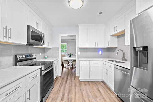 7528 Red Oak Ln, Charlotte, NC 28226 - kitchen featuring stainless steel appliances, light countertops, light wood-style floors, and white cabinets