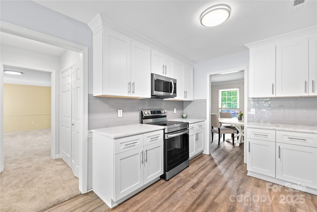7528 Red Oak Ln, Charlotte, NC 28226 - kitchen featuring stainless steel appliances, white cabinets, decorative backsplash, and light wood-style floors