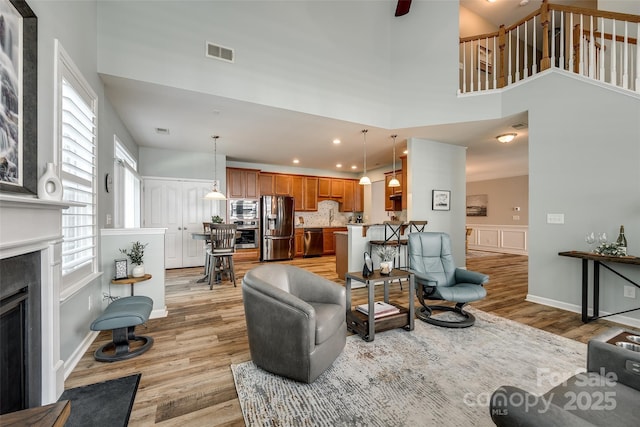 714 Deerbrook Ln, Tega Cay, SC 29708 - living area featuring light wood-style floors, a fireplace, a towering ceiling, recessed lighting, and wainscoting
