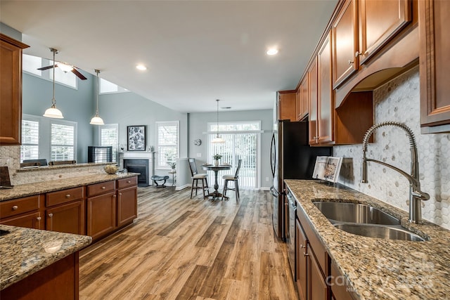 714 Deerbrook Ln, Tega Cay, SC 29708 - kitchen with brown cabinets, ceiling fan, light wood-type flooring, tasteful backsplash, and a fireplace