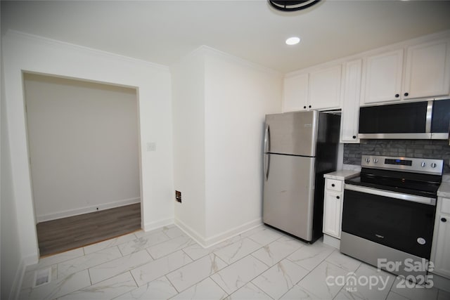 706 Mcintyre St, Monroe, NC 28110 - kitchen featuring appliances with stainless steel finishes, light marble finish flooring, baseboards, white cabinetry, and ornamental molding