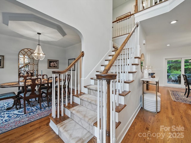 4644 Snow Dr, Harrisburg, NC 28075 - staircase with wood finished floors, arched walkways, a chandelier, recessed lighting, and baseboards