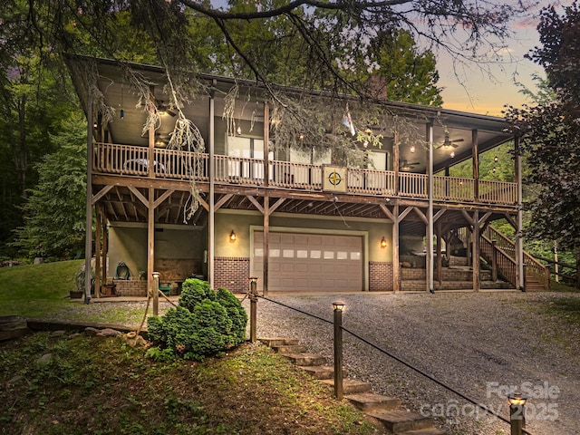 305 Pound Mill Branch Rd, Green Mountain, NC 28740 - view of front facade featuring stairway, a garage, driveway, a wooden deck, and stucco siding
