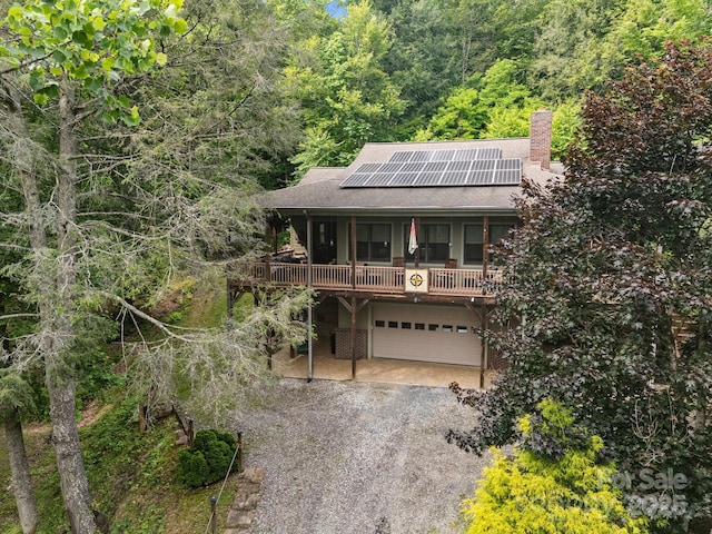 305 Pound Mill Branch Rd, Green Mountain, NC 28740 - view of front of property with a chimney, an attached garage, solar panels, a view of trees, and gravel driveway