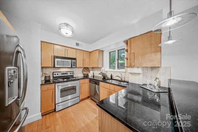 201 N Dotger Ave Unit C8, Charlotte, NC 28207 - kitchen featuring appliances with stainless steel finishes, a sink, light wood-type flooring, backsplash, and dark stone counters