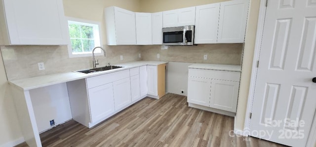 306 E Ratchford Ave, Gastonia, NC 28054 - kitchen featuring stainless steel microwave, a sink, light wood-style flooring, and white cabinetry