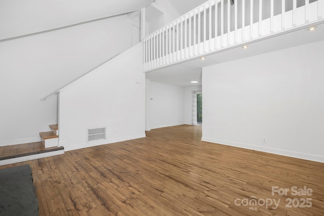 10101 Wood Ct, Charlotte, NC 28277 - unfurnished living room featuring a high ceiling, wood-type flooring, and stairway