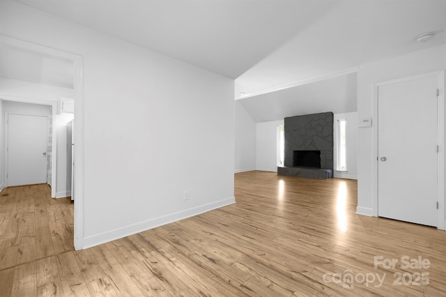 10101 Wood Ct, Charlotte, NC 28277 - unfurnished living room with light wood-style flooring, vaulted ceiling, and a stone fireplace