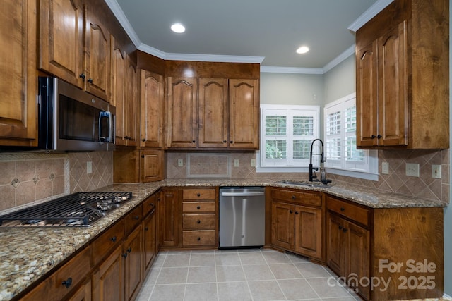 4672 Snow Dr, Harrisburg, NC 28075 - kitchen featuring stainless steel appliances, a sink, brown cabinetry, stone countertops, and ornamental molding