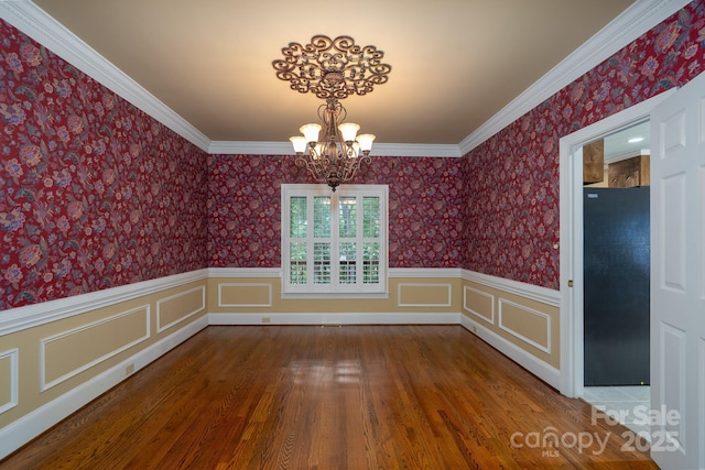 4672 Snow Dr, Harrisburg, NC 28075 - unfurnished dining area with a chandelier, wood finished floors, a wainscoted wall, wallpapered walls, and ornamental molding