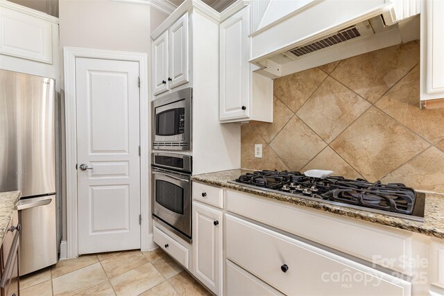 10106 Silverling Dr, Waxhaw, NC 28173 - kitchen with appliances with stainless steel finishes, range hood, tasteful backsplash, white cabinets, and light stone countertops