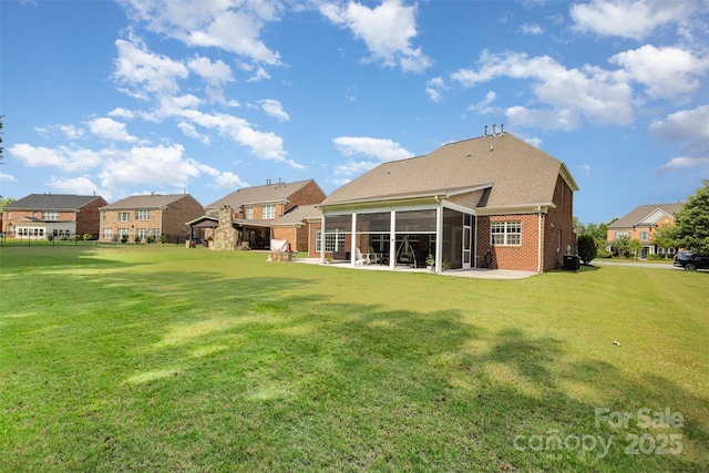 10106 Silverling Dr, Waxhaw, NC 28173 - rear view of house featuring a sunroom, a patio area, brick siding, a lawn, and a residential view